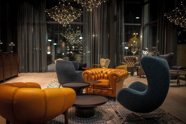 A modern lounge area with leather sofas, a blue armchair, and a patterned rug.