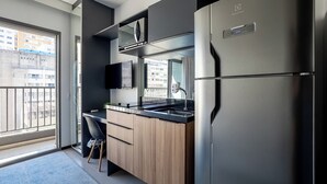 Une cuisine moderne dotée d’un four à micro-ondes encastré, d’un réfrigérateur en acier inoxydable et d’un plan de travail noir.