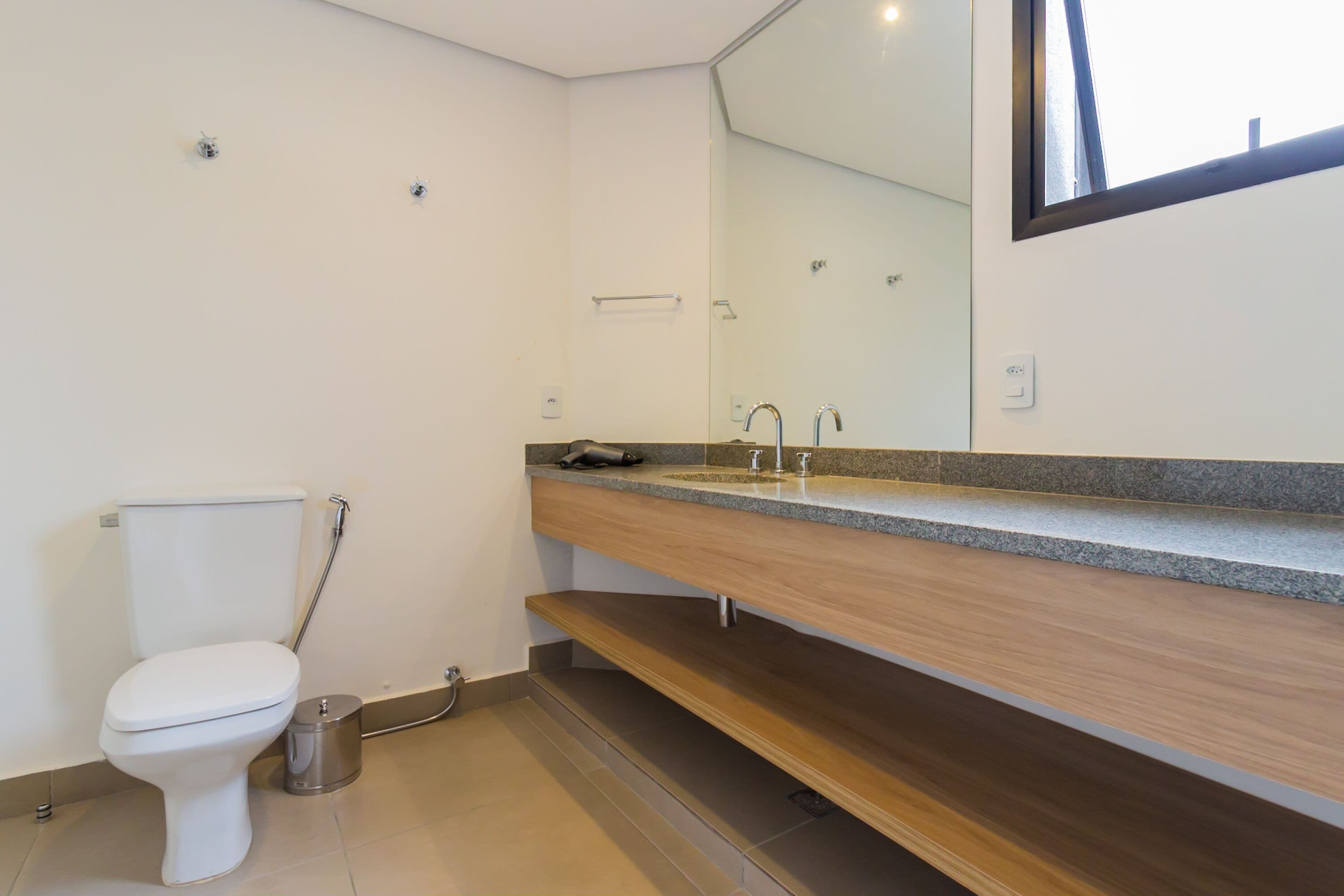 Et moderne badeværelse med toilet, vask og spejl.