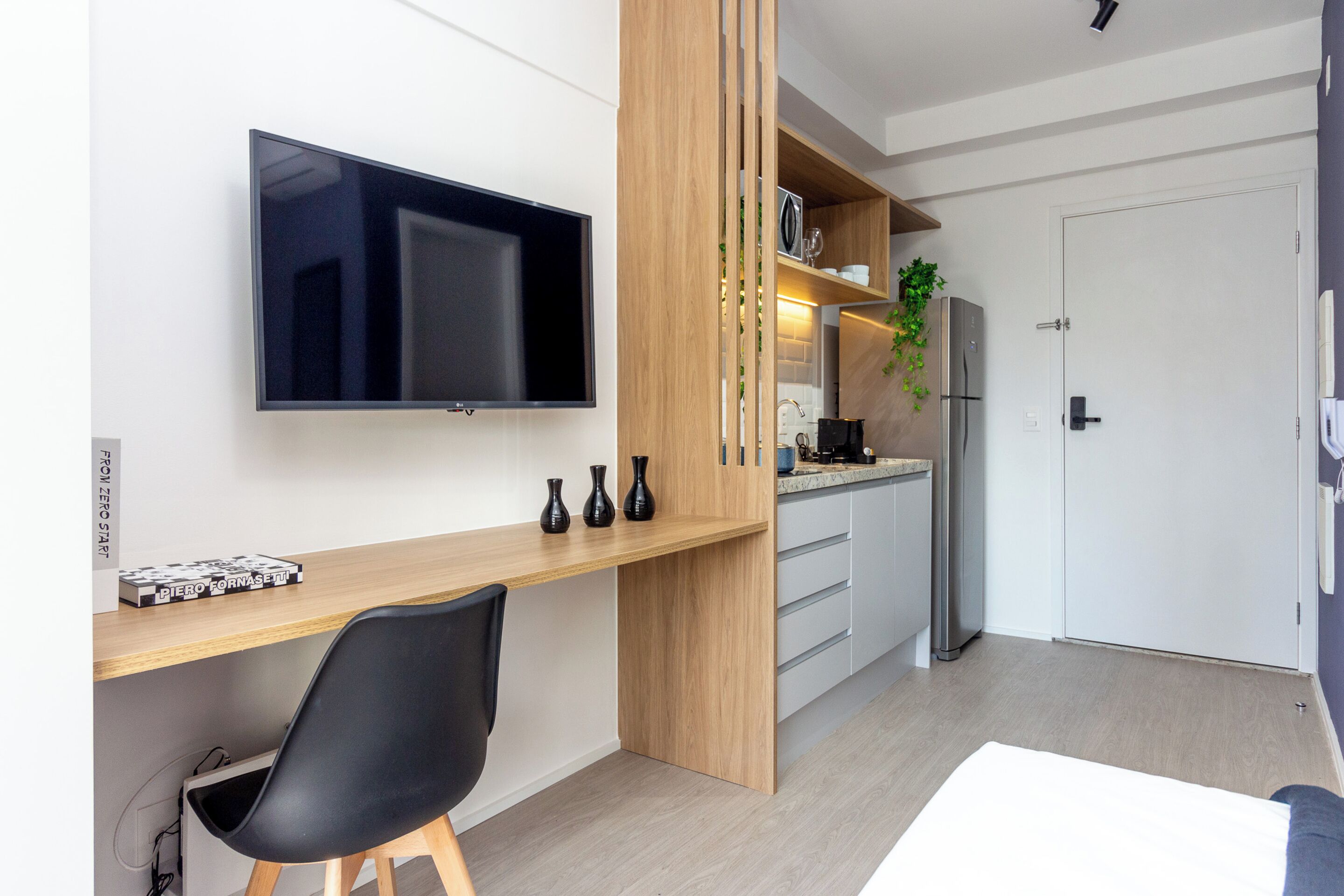 Una cucina moderna con TV integrata, mobili in legno e frigorifero.