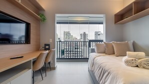 A modern hotel room with a large bed, a desk with a chair, a TV, and a balcony with a city view. - 360 SP Code (São Paulo)
