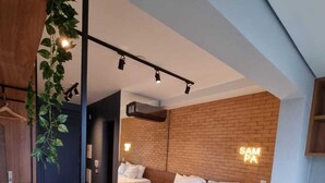 A modern bedroom with a large bed, a brick accent wall, and a neon sign. - 360 SP Code (São Paulo)