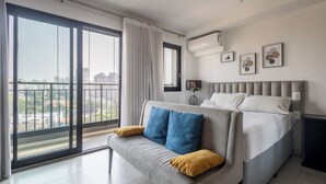 Ein modernes Schlafzimmer mit einem großen Bett, einer Couch und einer Glastür zum Balkon.
