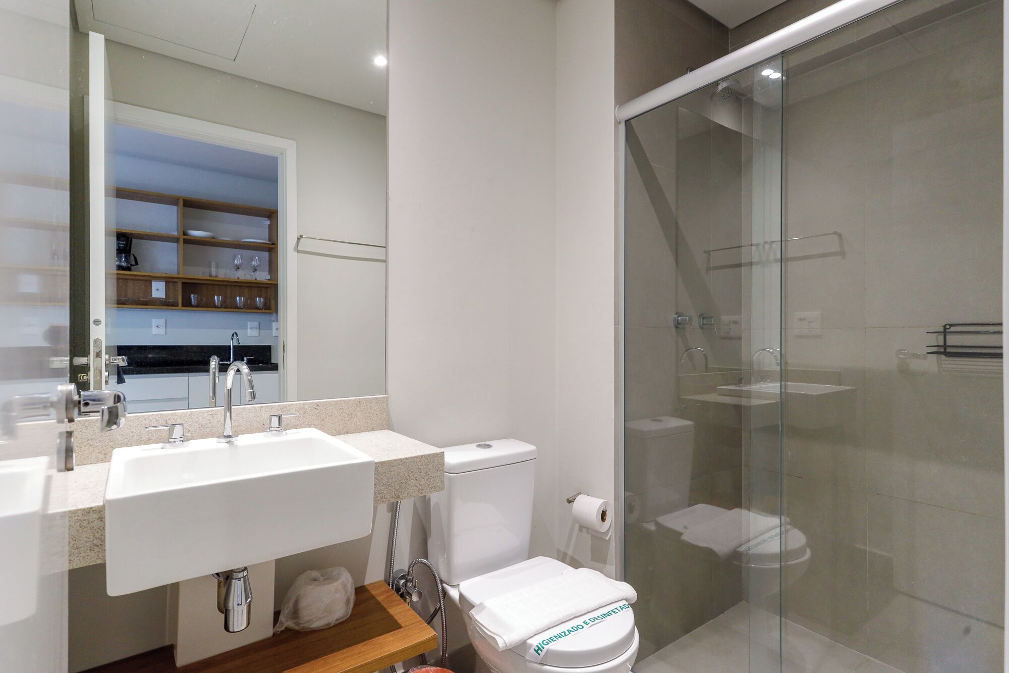 A modern bathroom with a glass shower enclosure, a dual sink vanity, and a toilet.