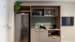 Eine kompakte Küche mit einem Edelstahlkühlschrank, einer Mikrowelle und einem kleinen Spülbecken.