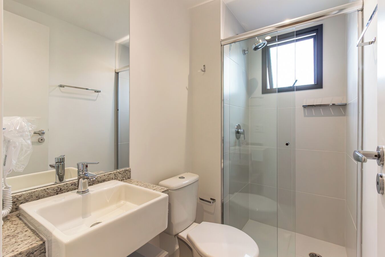 Un baño con lavamanos, inodoro y ducha envuelta en vidrio.