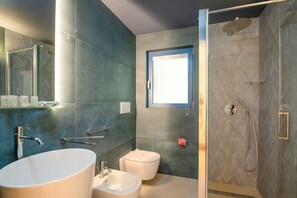 A modern bathroom with a freestanding bathtub, a toilet, and a glass-enclosed shower area.