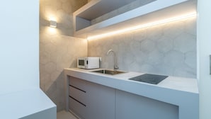 Eine moderne Küche mit weißer Arbeitsplatte, einer Mikrowelle, einem Spülbecken und einem integrierten Induktionskochfeld.