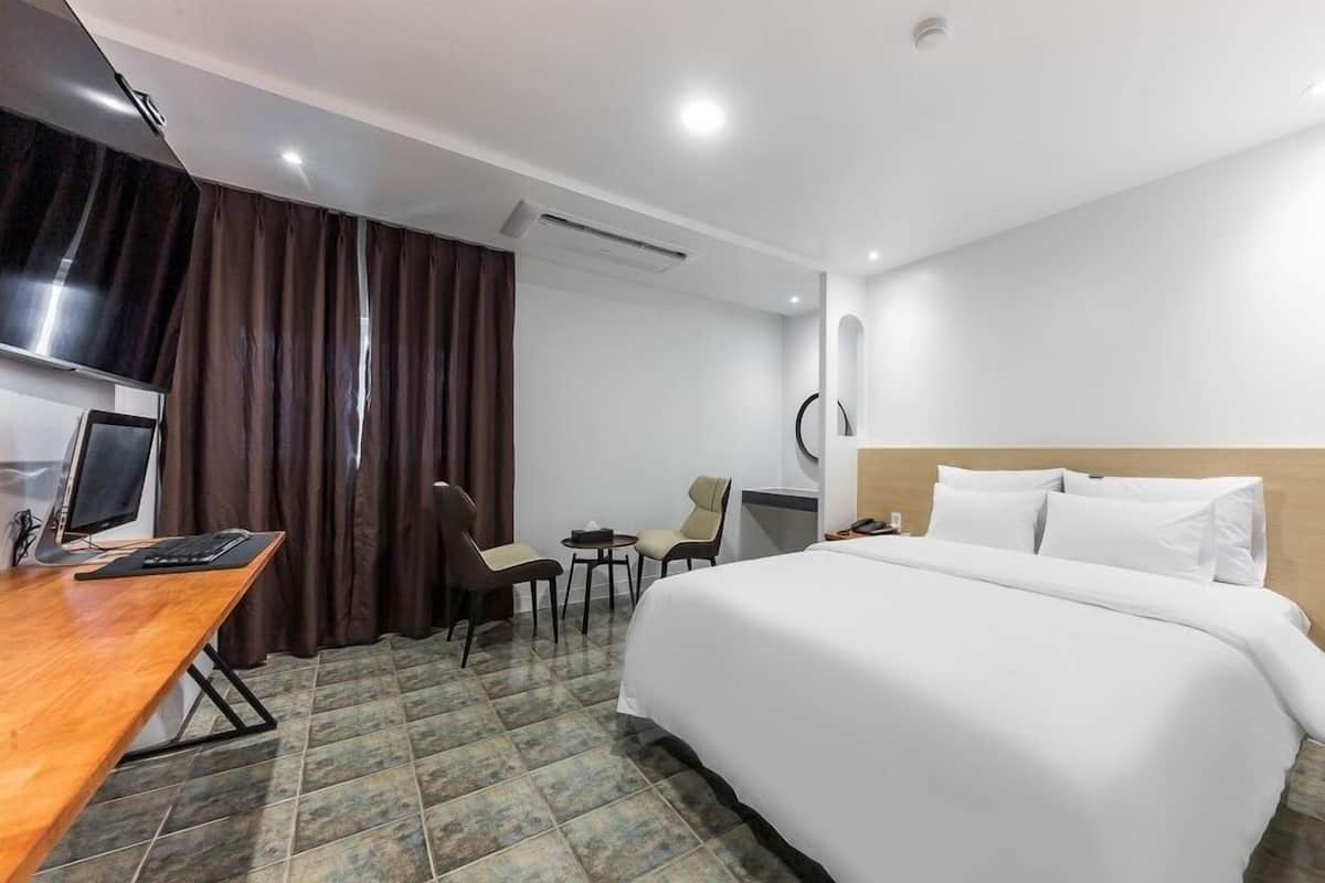 Una habitación de hotel con cama, escritorio, silla y televisor.