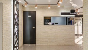 Zona de recepción de un hotel con una puerta negra, mostrador de recepción y un cartel que indica 'Información'.