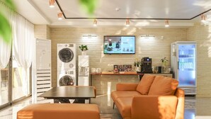Una sala de estar moderna con sofá, máquina de café, televisor y refrigerador.