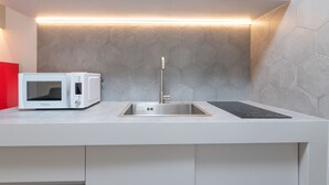 Una cocina moderna con microondas integrado, pileta de acero inoxidable y una elegante placa de inducción.