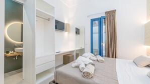 Una habitación de hotel moderna con cama, baño con lavamanos y espejo, y vista a través de una puerta.