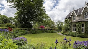 A well-maintained garden with a variety of flowers and a large tree. - Blackstairs Shepherds Huts (Knocksquire)