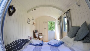 A cozy room with a bed, a chair, and a door leading outside. - Blackstairs Shepherds Huts (Knocksquire)