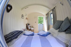 A cozy room with a bed, a chair, and a door leading outside.