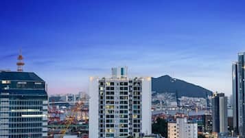 Un edificio alto con varios pisos, probablemente un hotel o edificio residencial, con vista a un puerto y grúas al fondo.