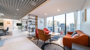 A modern living room with a city view, a kitchen area, and a dining space.