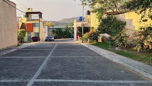 A quiet residential street with houses on both sides, a parked car, and a clear view of the distant hills. - Cuernavaca (Emiliano Zapata)