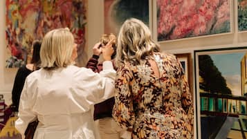 Un grupo de personas en una galería con grandes pinturas abstractas en las paredes.