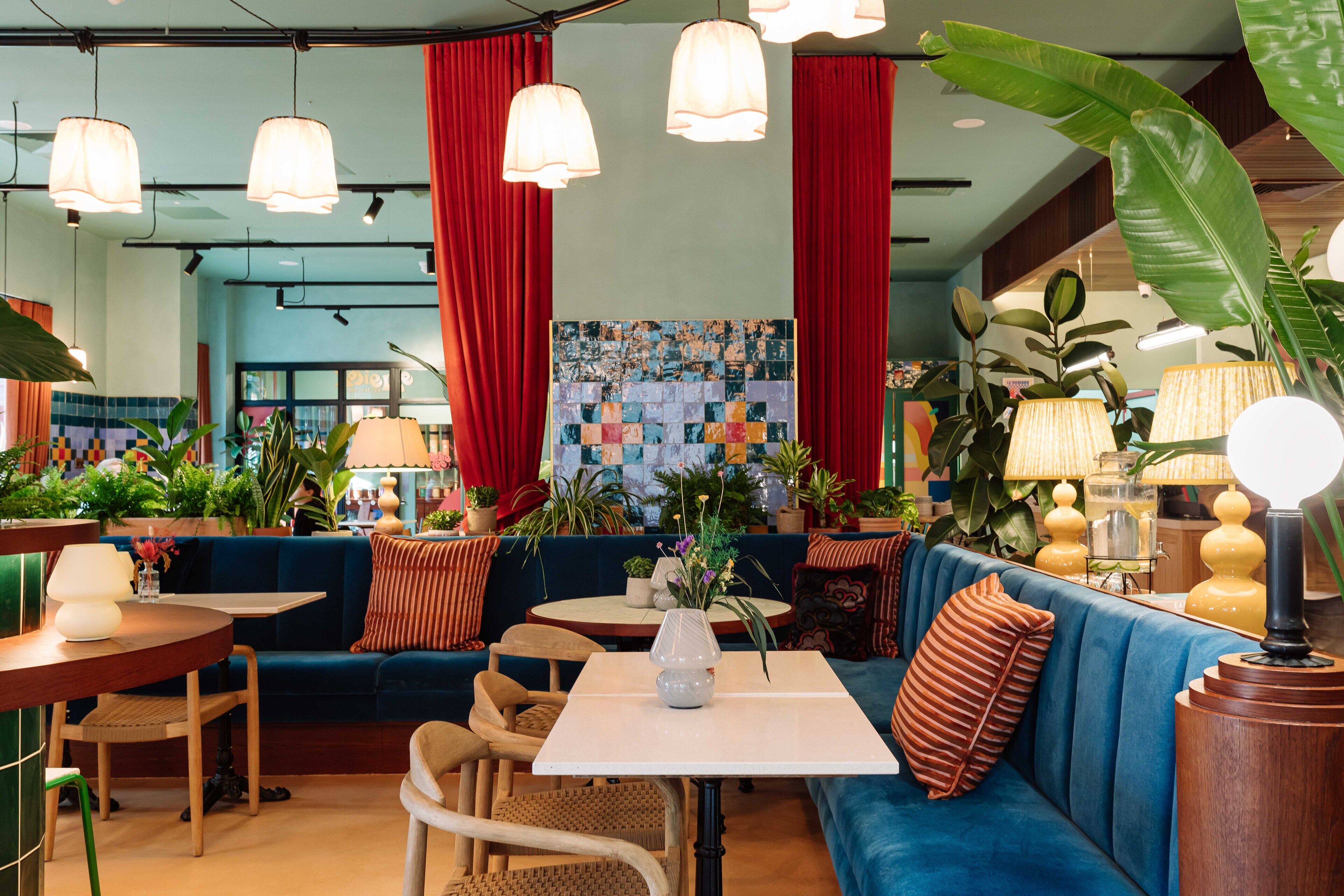 A modern lounge area with seating, tables, and hanging lamps.