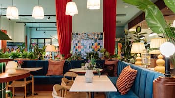 A modern lounge area with seating, tables, and hanging lamps.