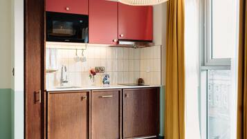 Cucina con mobili in legno, forno a microonde e finestra con tende.