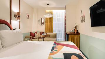 Une chambre d’hôtel avec un grand lit, un canapé, une petite table avec une lampe et un téléviseur fixé au mur.