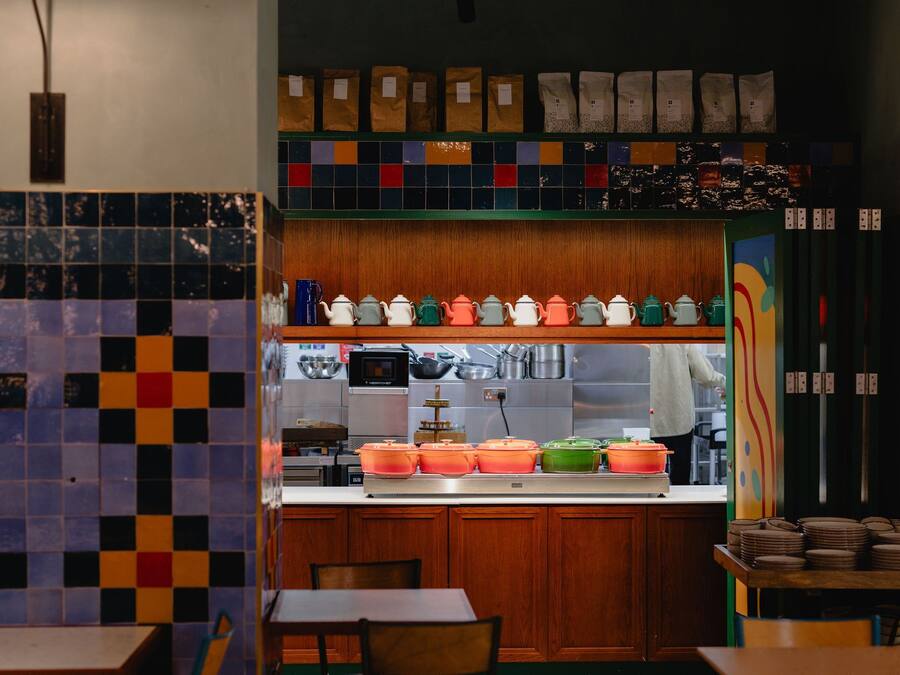 A kitchen with wooden cabinets, a tiled backsplash, and a variety of kitchenware on shelves.