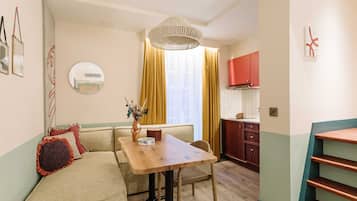 Un espacio habitable pequeño con sofá, mesa de comedor y zona de cocina.