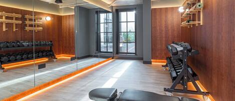 A gym with a bench press, dumbbells, and a squat rack.