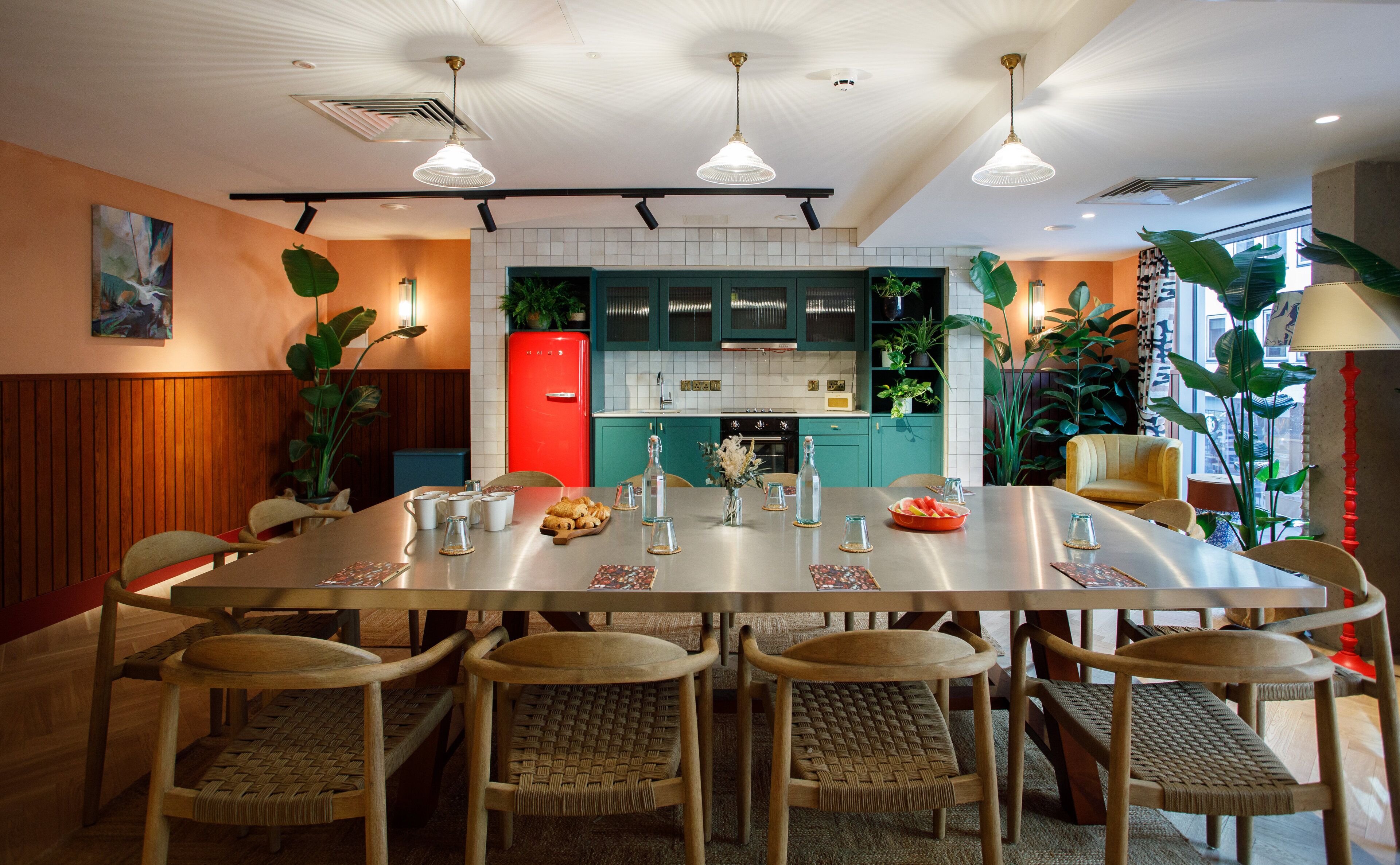 A modern kitchen with a dining area, featuring a large island, wooden chairs, and various kitchen appliances.