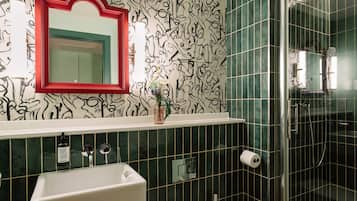 A bathroom with a white sink, a red-framed mirror, and a shower area with a glass door.
