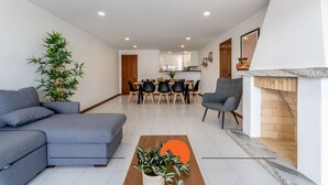 A modern living room with a grey sofa, a wooden coffee table with plants, and a dining area with a wooden table and chairs. - #169 T3 Medronheira by Home Holidays (Albufeira)