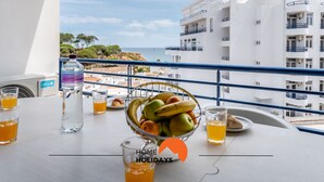 A balcony with a table set for breakfast, including a fruit bowl, glasses of orange juice, and a bottle of water. - #169 T3 Medronheira by Home Holidays (Albufeira)
