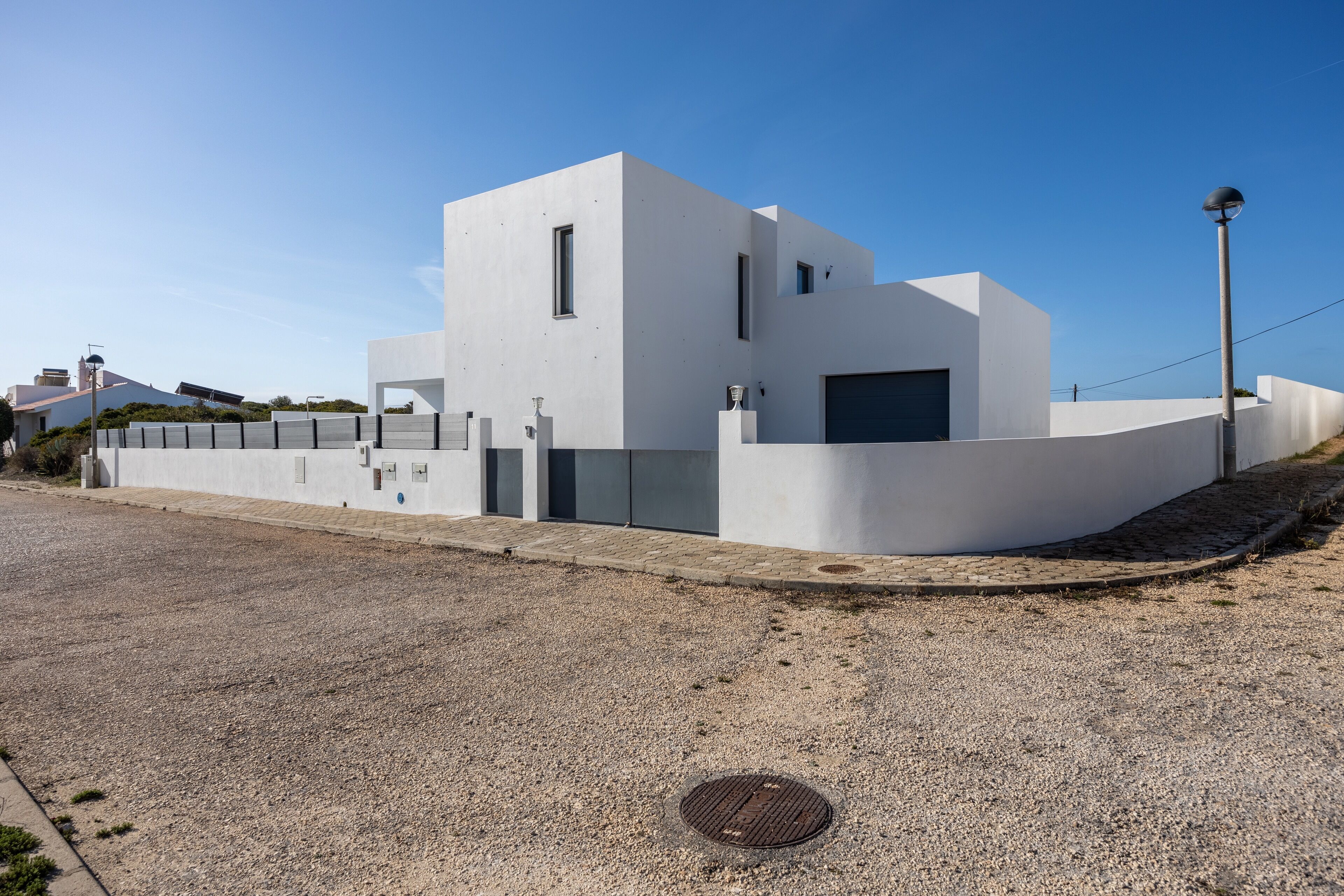 Un edificio moderno con techo plano, una puerta de garaje grande y un camino de entrada de grava.