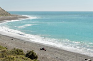 Una playa con una duna, una persona manejando un buggy y el océano.