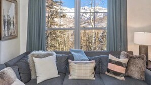 A living room with a couch, pillows, and a large window with curtains. - Luxury Mountain Village Retreat | Cassidy Ridge 4BR with Panoramic Views (Mountain Village)