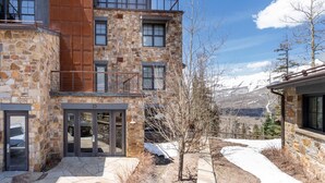 A multi-story stone building with a balcony, a door, and a view of snow-capped mountains. - Luxury Mountain Village Retreat | Cassidy Ridge 4BR with Panoramic Views (Mountain Village)