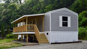 A two-story cabin with a covered porch and a small deck.