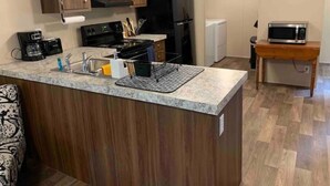 A compact kitchen with wooden cabinets, a built-in stove, a microwave, and a sink.