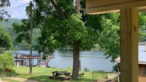 A lakeside view with a dock, picnic table, and a wooden deck.