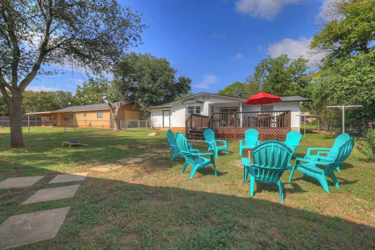 A backyard with a patio area, outdoor chairs, and a red umbrella.
