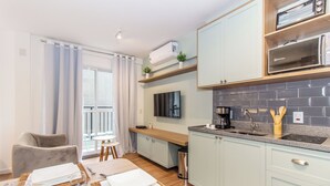 A modern kitchen with light blue cabinets, a built-in oven, and a flat-screen TV. - 360 For Consolação (São Paulo)