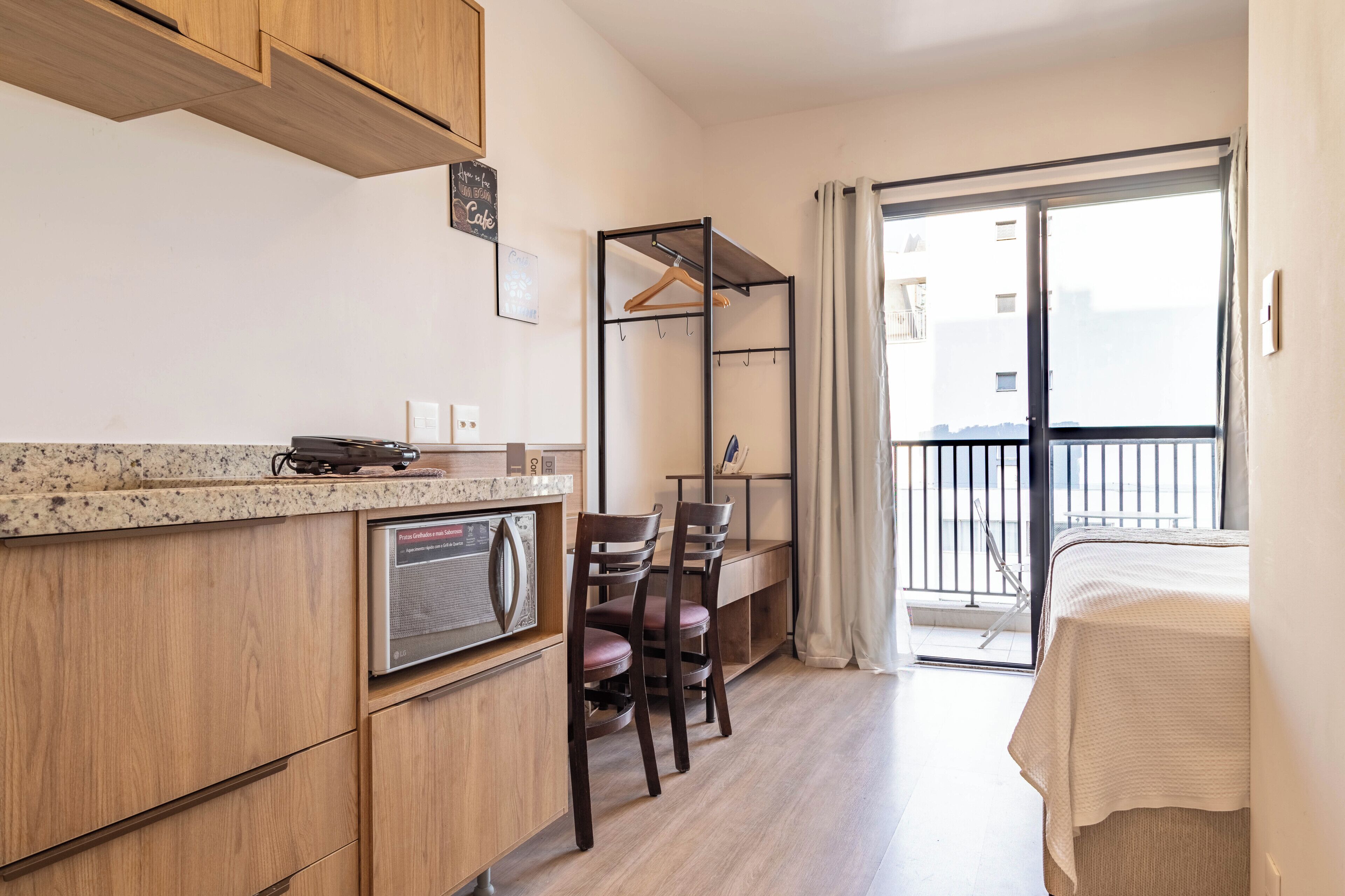 A compact kitchen with wooden cabinets, a countertop, a radio, and a dining area with chairs and a table.
