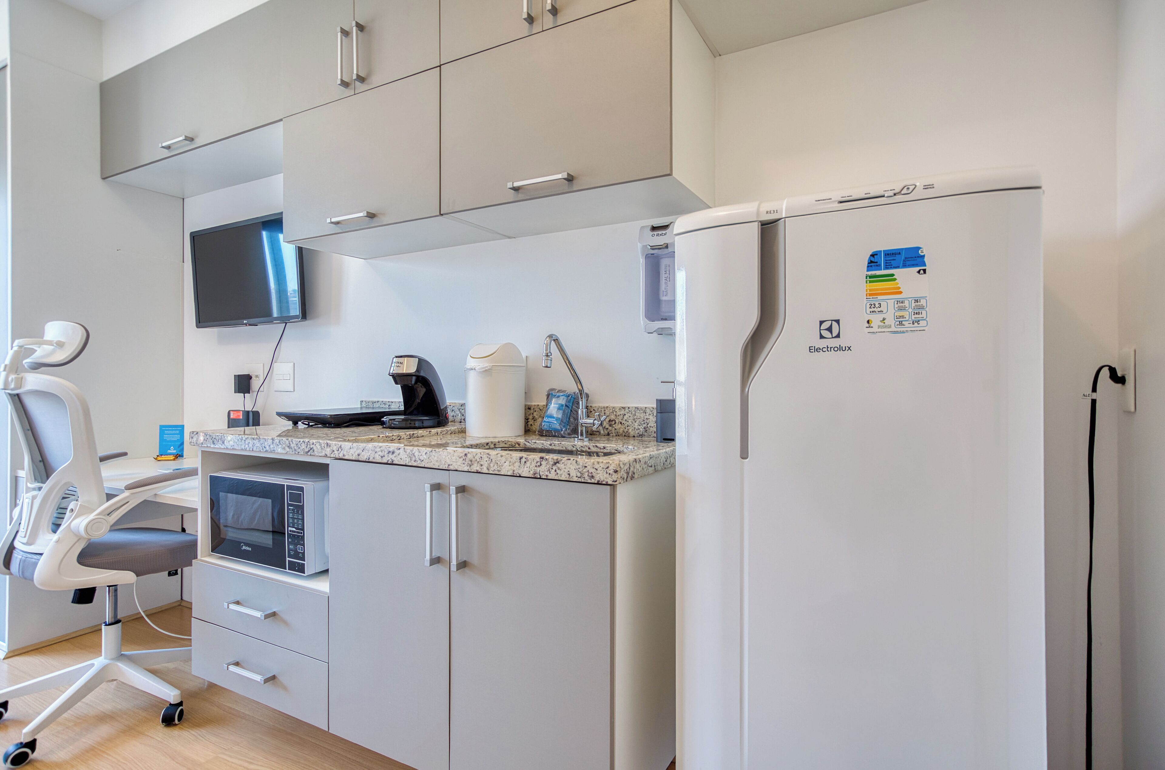 A modern kitchen with a built-in microwave, coffee maker, and a refrigerator with a water dispenser.