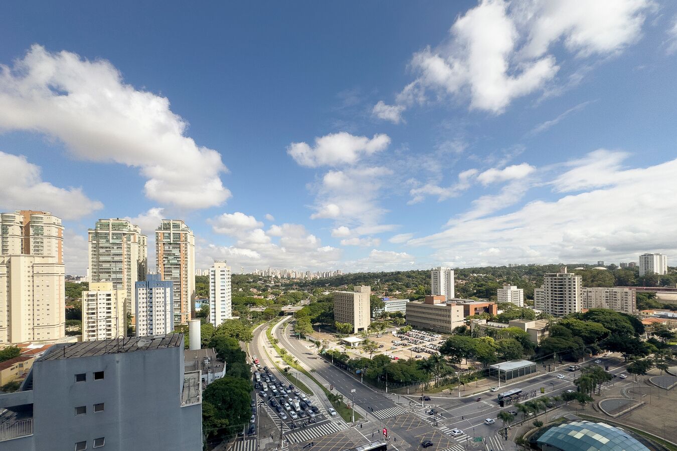 Une vue urbaine avec de hauts immeubles, un carrefour animé et un ciel dégagé.