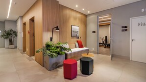 Et moderne receptionsområde med en træreception, en potteplante, en rød og sort kube samt en sort kube.