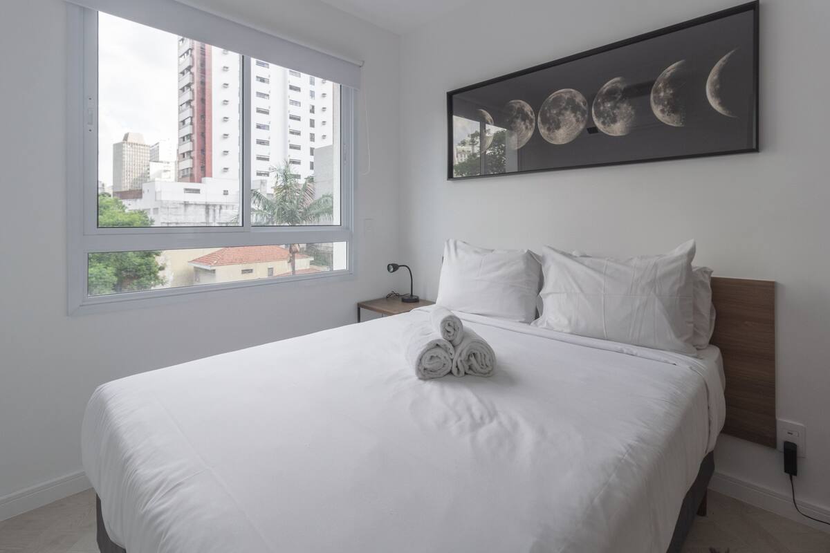 Ein Hotelzimmer mit einem großen Bett, einem Fenster mit Stadtblick und einem Wandbild der Mondphasen.