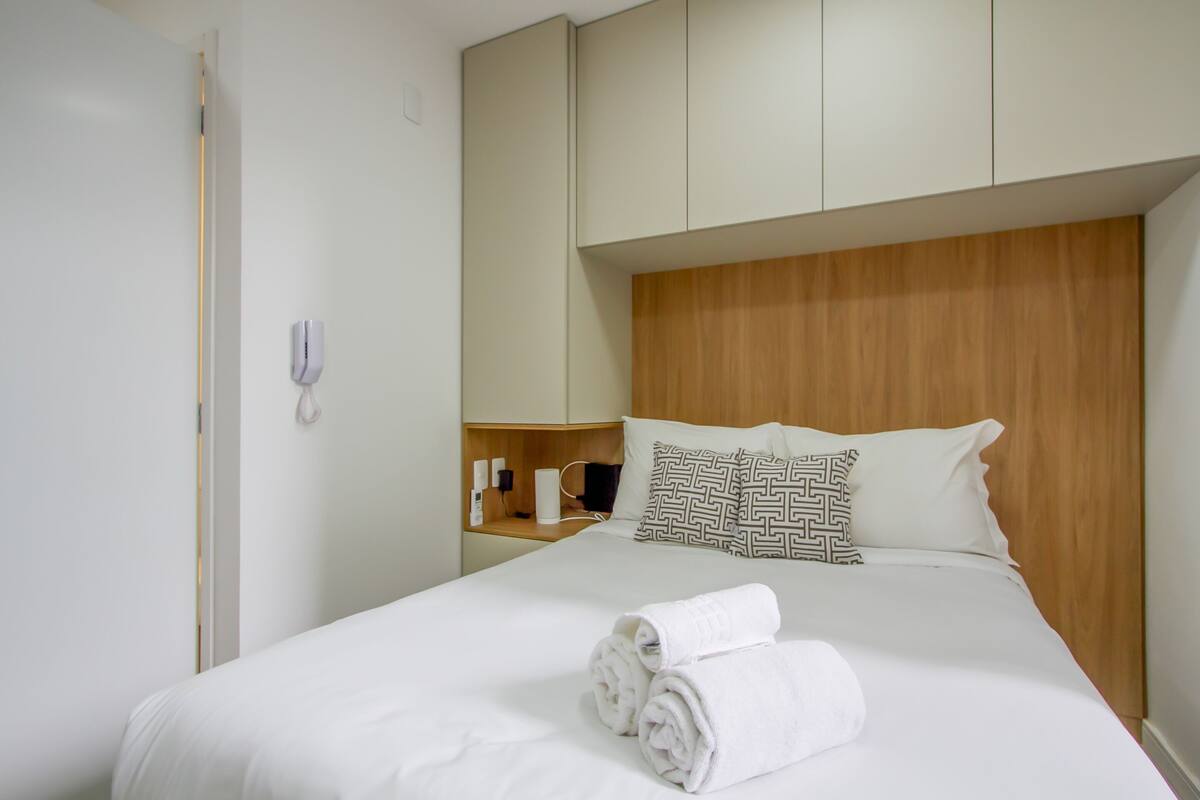 Ein Hotelzimmer mit einem Bett, einem Holzkopfende, einem Nachttisch mit Lampe und einem Telefon.